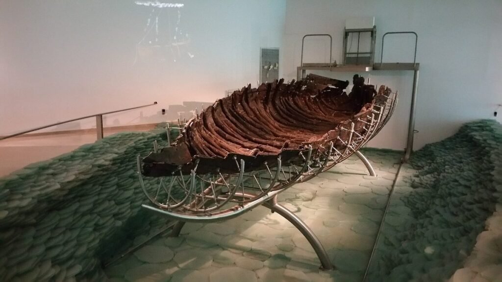 Drewniany kadłub starożytnej łodzi rybackiej na metalowym stelażu w muzeum